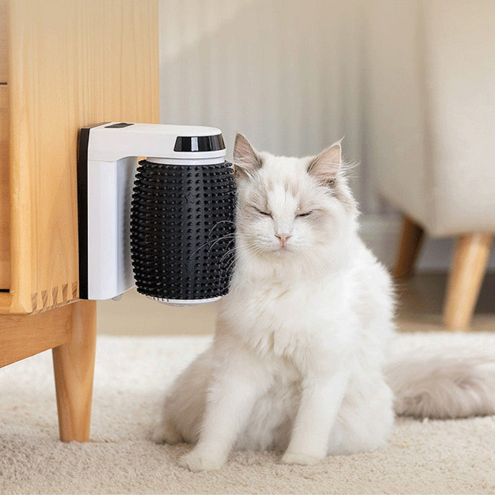 Vit katt gnuggar mot automatisk kattborste monterad på möbel