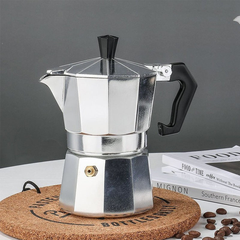 Moka pot på korkunderlägg med kaffebönor och böcker