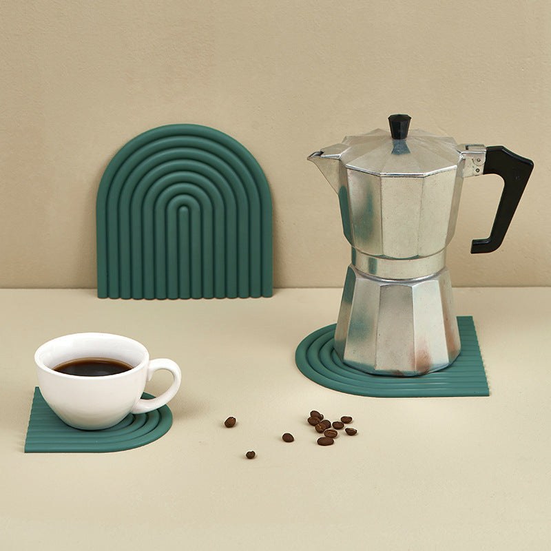 Moka pot på grön silikon-underlägg med kaffekopp