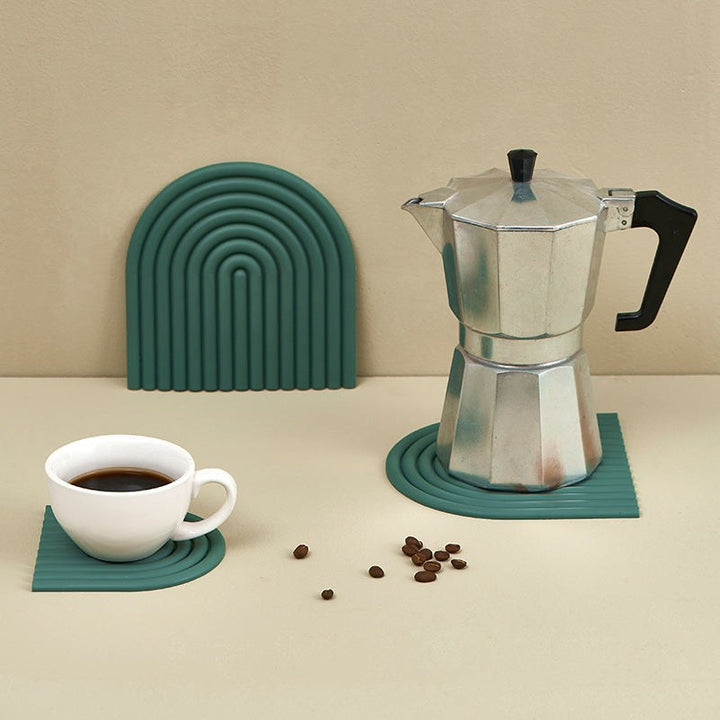 Moka pot på grön silikon-underlägg med kaffekopp